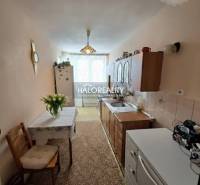 A kitchen in a 3-room apartment with a carpet, kitchen unit, and dining table.