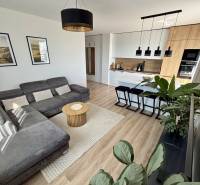 Living room in a three-room apartment with a wooden decor floor and a gray sofa.