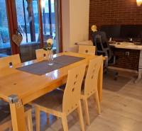 Dining room in a family house with a wood-patterned floor, wooden table, office-work corner.