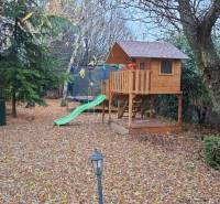 A garden at a family house in Bohdanovce nad Trnavou with a children's wooden playhouse and a trampoline.