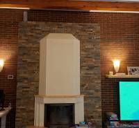 Interior of a family house with a fireplace and a television screen on a brick wall.
