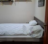 Bedroom in a family house with a bed, shelves, and a picture, floor with wooden decor.