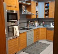 A kitchen in a family house with wooden cabinets and appliances, tiled floor.