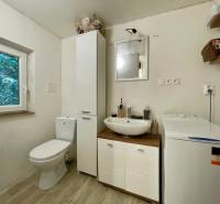 Bathroom in a cabin with a sink, washing machine, and toilet, floor with wooden decor.