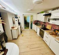 A kitchen in a cabin with a wood-decor floor and white furniture.