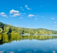 A lake in a wooded landscape with a blue sky near Kučišdorská Valley in Pezinok.