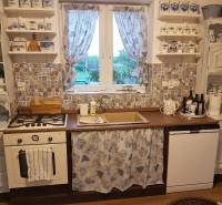 A kitchen in a family house with a country style, patterned tiles, blue curtains.