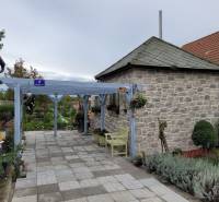 A family house in Okoličná na Ostrove with a stone annex and garden benches.