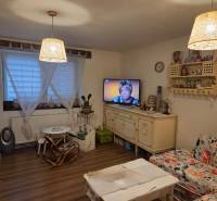 Living room with wood-patterned flooring, floral sofa, and television in a family house.