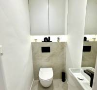 Bathroom in a 4-room apartment with a simple sink and wall-mounted toilet, light tiles.