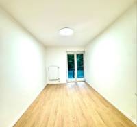 White room in a 4-room apartment with a wood-patterned floor and balcony doors.