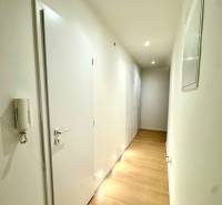 A hallway with light walls and a floor with a wooden decor in a 4-room apartment.