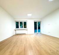 Interior of a 4-room apartment with a wooden decor floor, white walls, and windows.