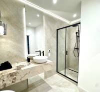 Bathroom with a shower, a sink on a stone countertop, and light tiling in a 4-room apartment.