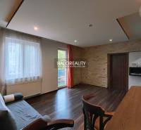Living room in a two-room apartment with a wooden decor floor and a French window.