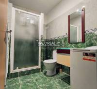 Bathroom in a 2-room apartment with a toilet, shower, washing machine, and green tiles.