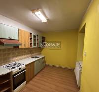 A kitchen in a 2-room apartment with a wooden decor floor and yellow walls.