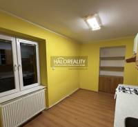 A kitchen in a 2-room apartment with yellow walls and a wooden decor floor.