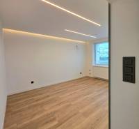 A room with a wooden decor floor in a 3-room apartment, with LED ceiling lighting.