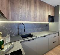 A kitchen in a 3-room apartment with a kitchen unit, a wooden decor floor, and marble tiles.