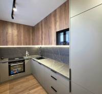 The kitchen of a three-room apartment with a wooden-patterned floor and speckled gray countertops.