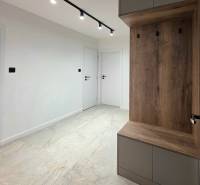 A hallway in a 3-room apartment with white walls, ceramic flooring, and wall cabinets.
