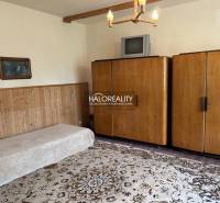 A room in a family house with a sofa, wooden cabinets, and a television on the carpet.