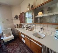 A kitchen in a family house with wooden cabinets and a cozy seating area by the table.