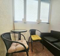 A balcony in a 3-room apartment with seating, chairs, and a table.