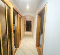 A hallway with a tiled floor, doors with a wooden decor in a 3-room apartment.