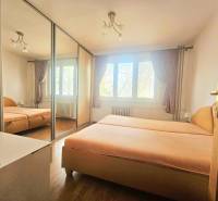 Bedroom in a 3-room apartment with a bed, built-in wardrobe, and floor with wooden decor.