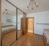 A bedroom in a 3-room apartment with a wooden decor floor and a large mirrored wardrobe.