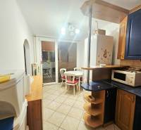 A kitchen with a dining area in a 3-room apartment, white walls, blue cabinets, ceramic tiles.