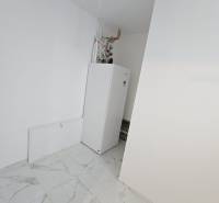 A white room with a boiler and tiles with a marble pattern in a family house.