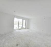 Empty room in a family house with large windows and raw flooring.