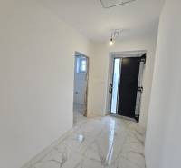 A hallway with white walls and marble tiles in a family house.