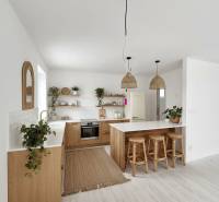 A kitchen in a family house with wooden decor, bar stools, and plants.
