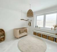 Children's room in a family house with a wooden crib and a carpet in soft colors.