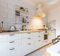 A kitchen in a 2-room apartment with a wooden decor floor and white cabinets.