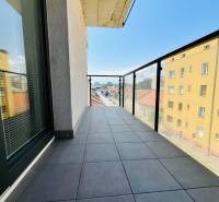 Balcony with tiles and glass railing, view of the street in a 3-room apartment.