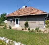 A family house in Nevidzany with a garden, lawn, and fence, under a blue sky.
