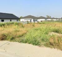 A residential plot in Kvetoslavov on Bazová Street with greenery and surrounding houses.