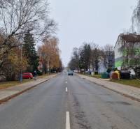 Banícka Street in Poprad is lined with trees and buildings, suitable for a 2-room apartment.