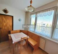 Dining room in a 3-room apartment with a wooden decor floor and large windows.