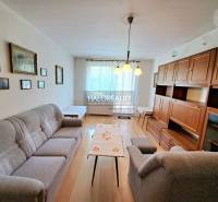Living room with light, wood-patterned flooring, and furniture in a three-room apartment.