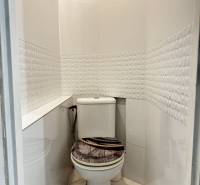 Bathroom with toilet in a 3-room apartment, tiles with a geometric pattern and floor with wood decor.