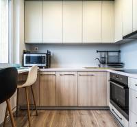 A kitchen in a 2-room apartment with a wooden decor floor and light furniture.