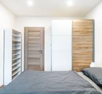A bedroom in a 2-room apartment with a large wardrobe and a shelving unit.