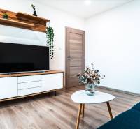 Living room with a television, wardrobe, stool, and wooden decor flooring in a two-room apartment.