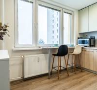 A kitchen in a 2-room apartment with a bar counter, stools, and a floor with a wooden decor.